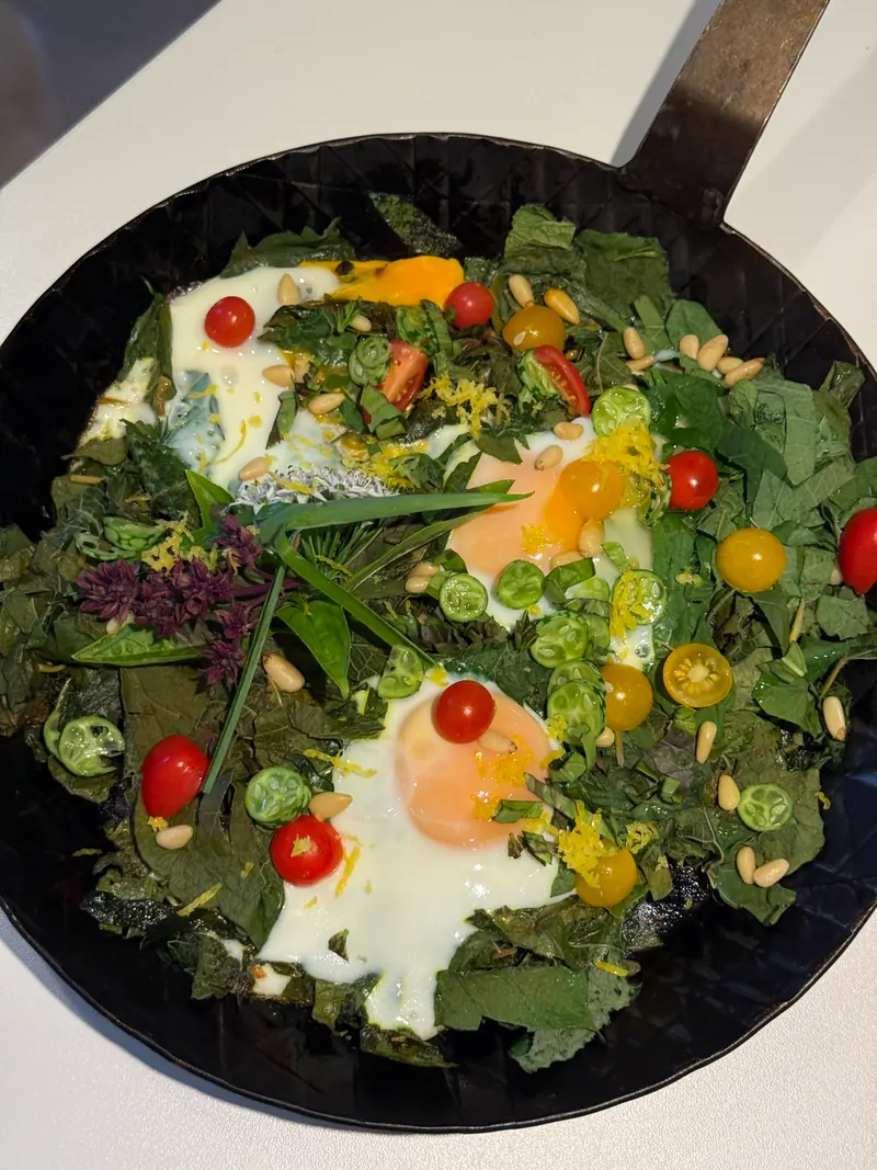 Kräuterpfanne mit Spiegeleiern, Kirschtomaten und Pinienkernen von oben